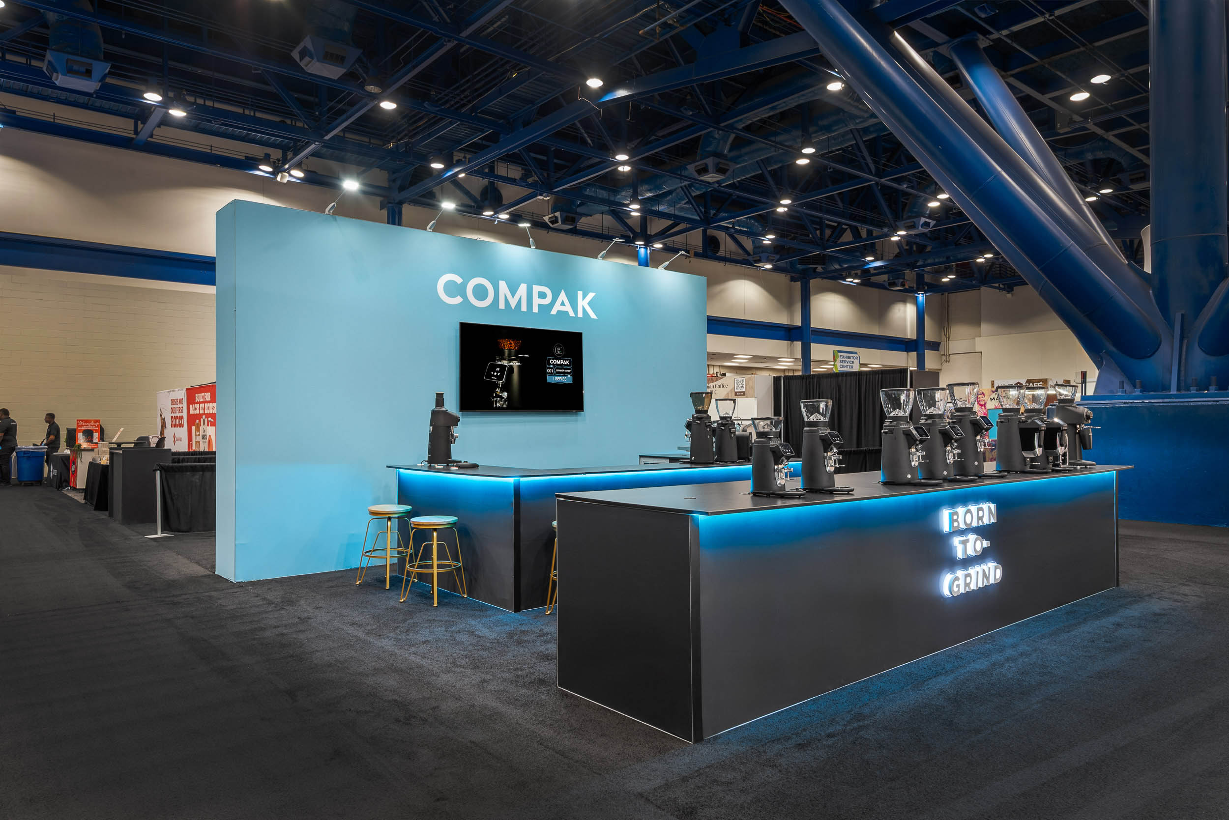 Custom trade show booth display with illuminated branding and product demonstration counters at an exhibition event