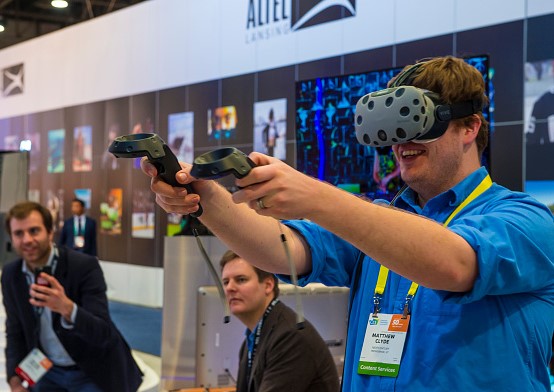 A person wearing virtual reality goggles in a trade show booth